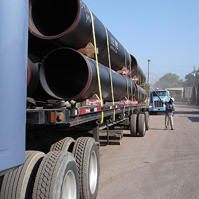 Man checking industrial pipes loaded on a semi.