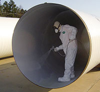 Man in protective suit spraying coat on pipe interior.